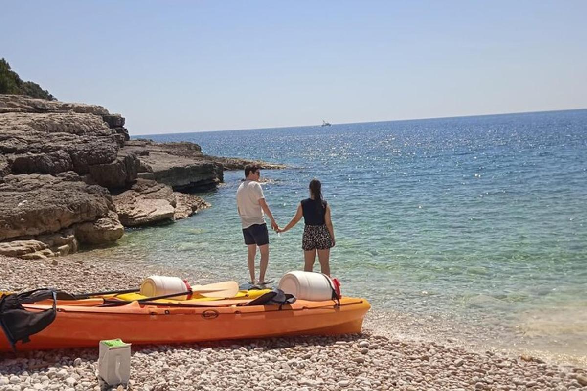 muškarac i žena stoje pored kajaka na plaži