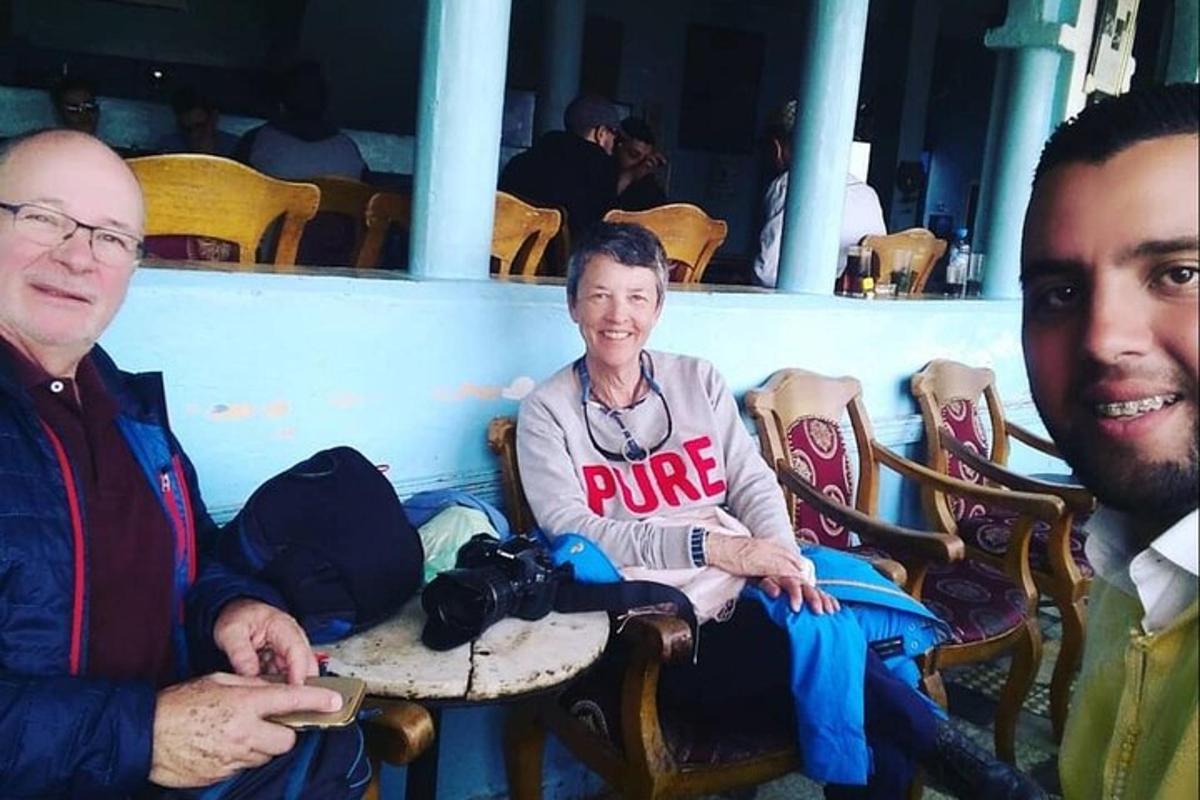 hai người đàn ông và một người phụ nữ ngồi trên ghế với một chiếc máy ảnh