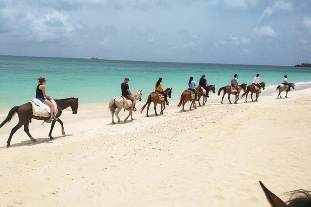 un grup de persones muntant a cavall a la platja