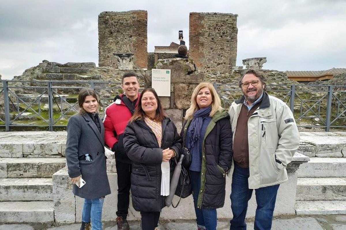 skupina ljudi, ki stojijo pred ruševinami