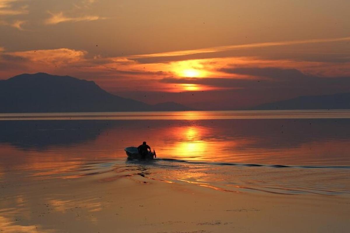 ein Mann, der bei Sonnenuntergang auf einem Surfbrett im Wasser sitzt