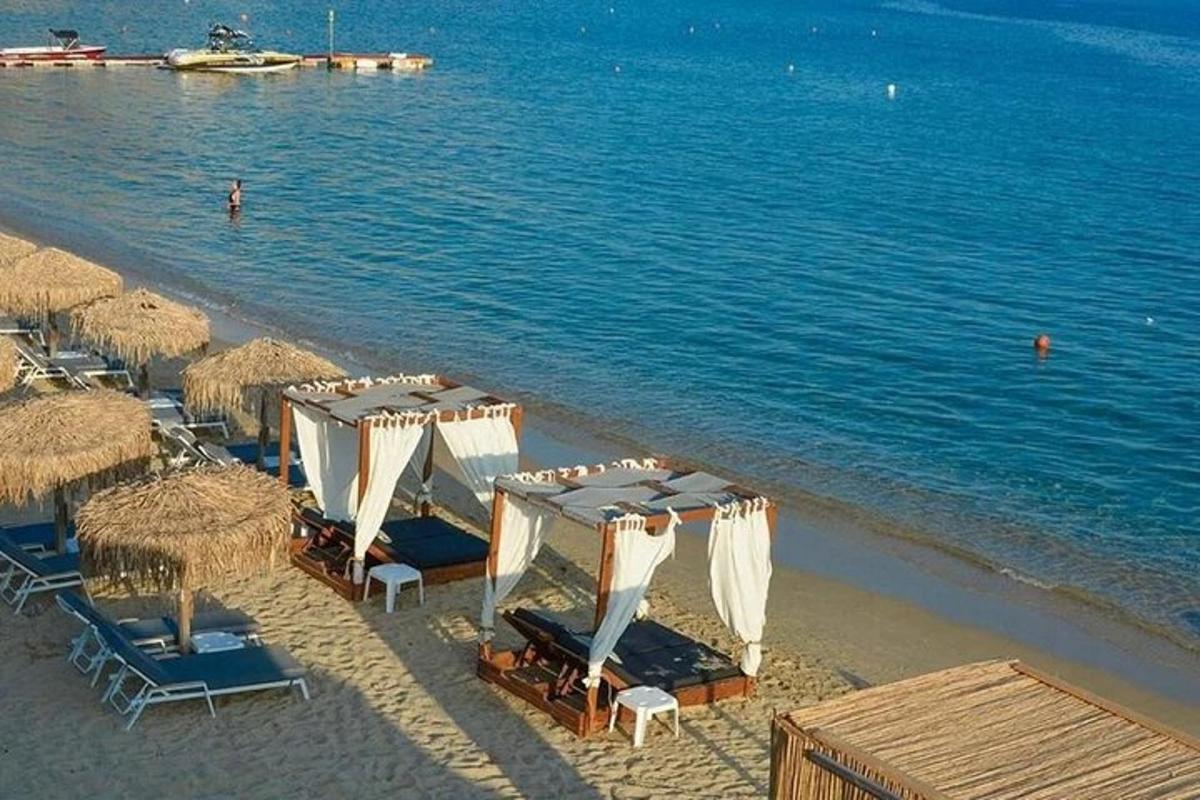 Una playa con sillas y sombrillas y el agua.