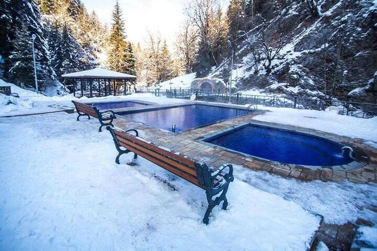 due panchine nella neve accanto a una piscina