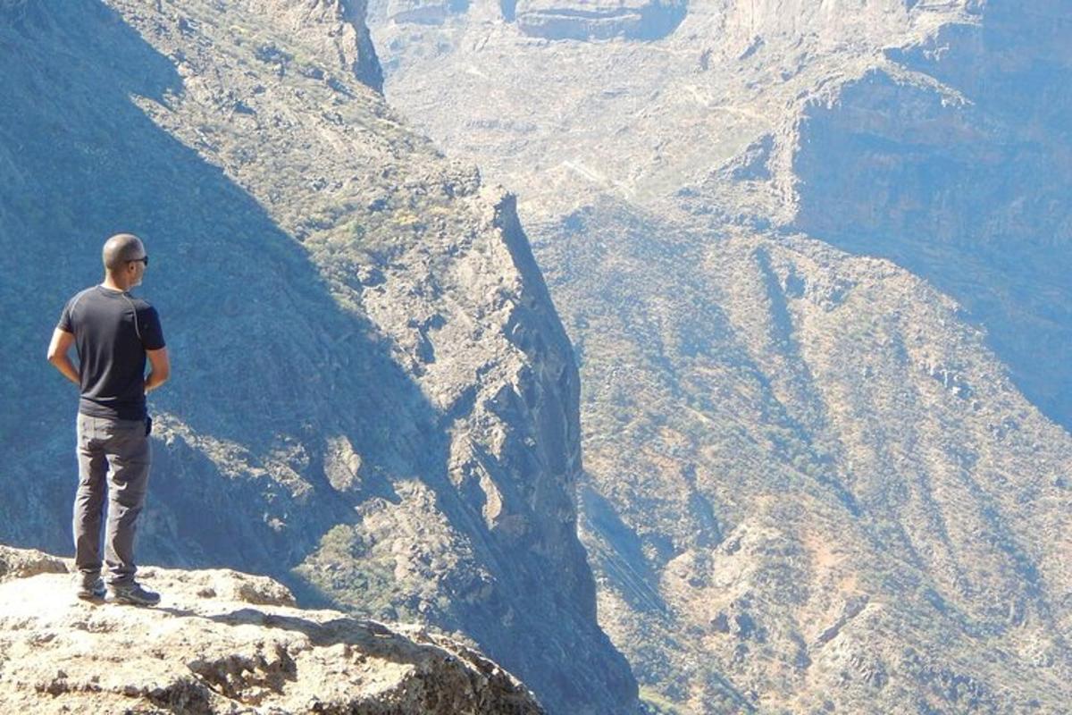 Ένας άντρας στέκεται στην άκρη ενός βουνού κοιτάζοντας ένα φαράγγι