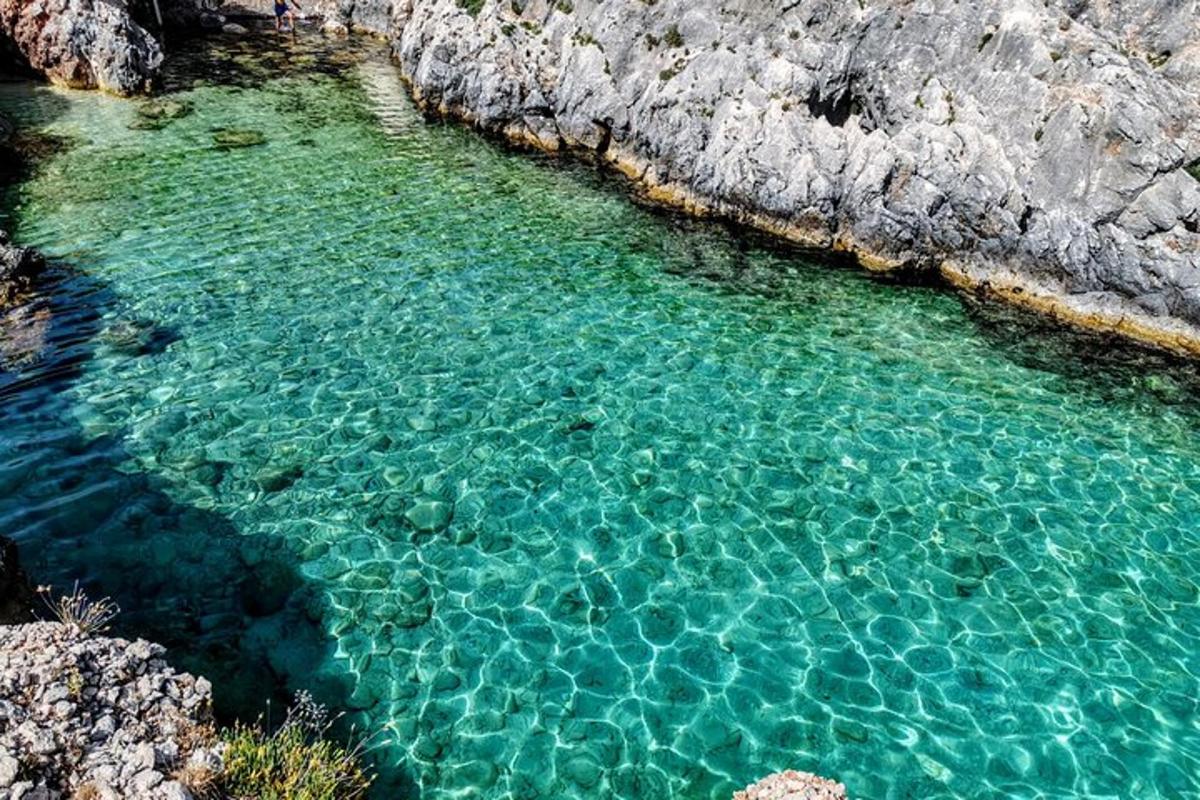 ein Pool mit klarem, blauem Wasser neben einigen Felsen