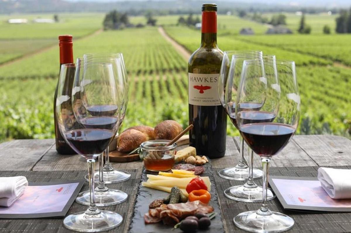 Una mesa de madera con copas de vino y comida encima.