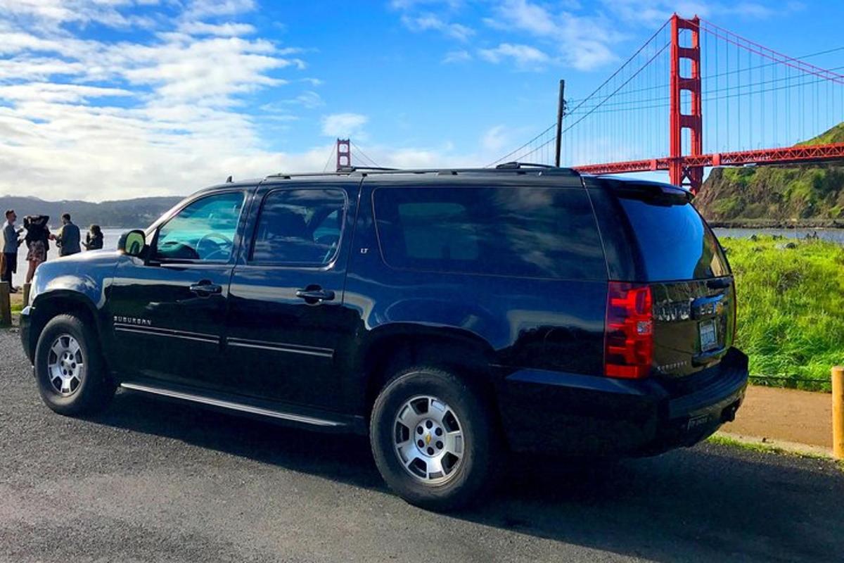Una camioneta azul estacionada frente a un puente Golden Gate.