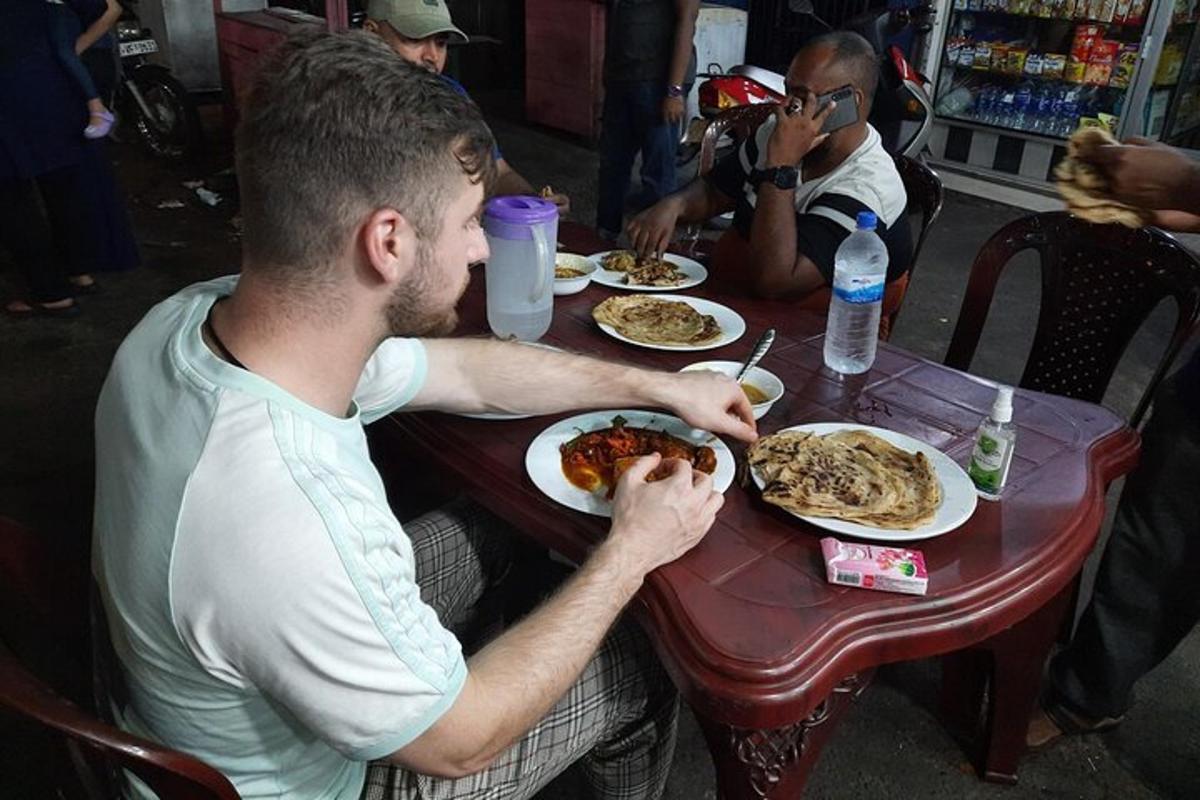 un hombre sentado en una mesa comiendo un plato de comida