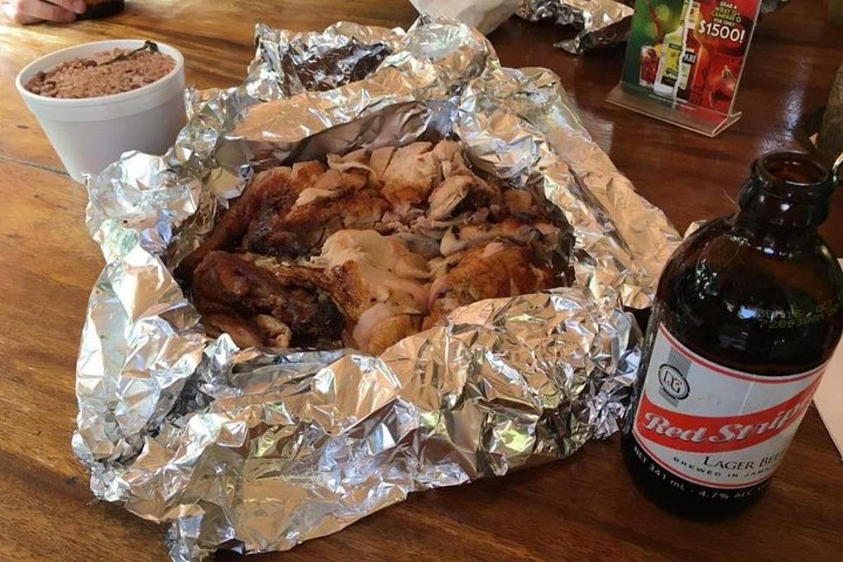 um frango embrulhado em papel alumínio ao lado de uma garrafa de cerveja
