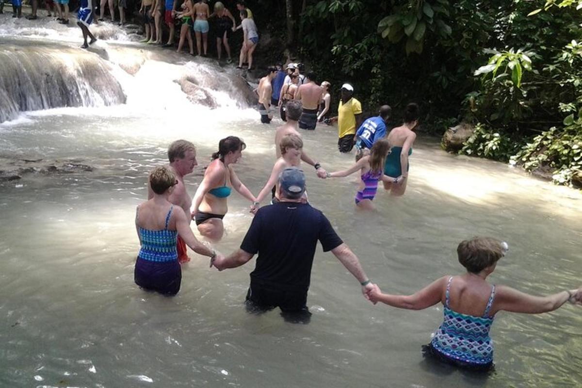 un gruppo di persone che si tengono per mano nell'acqua vicino a una cascata
