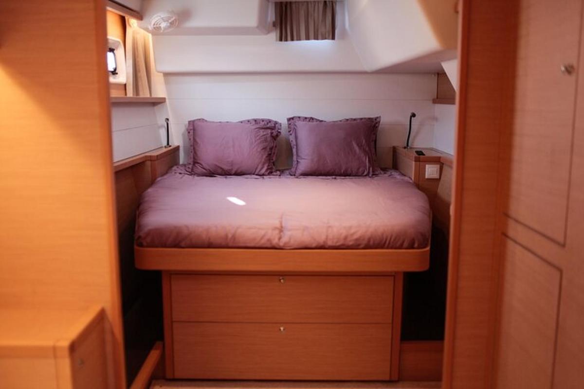 een klein bed met paarse kussens in een kleine kamer