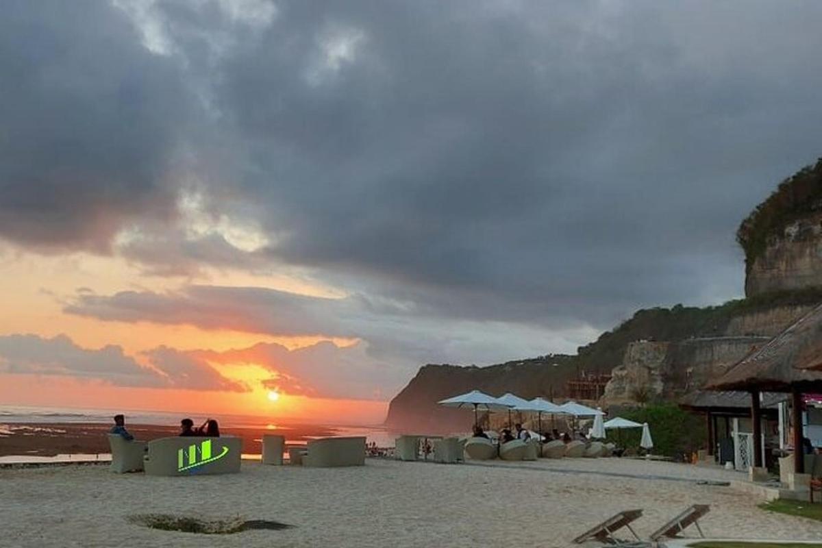 Un grupo de personas sentadas en la playa al atardecer