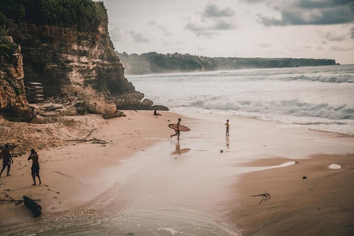 Un grupo de personas caminando por una playa con una tabla de surf.