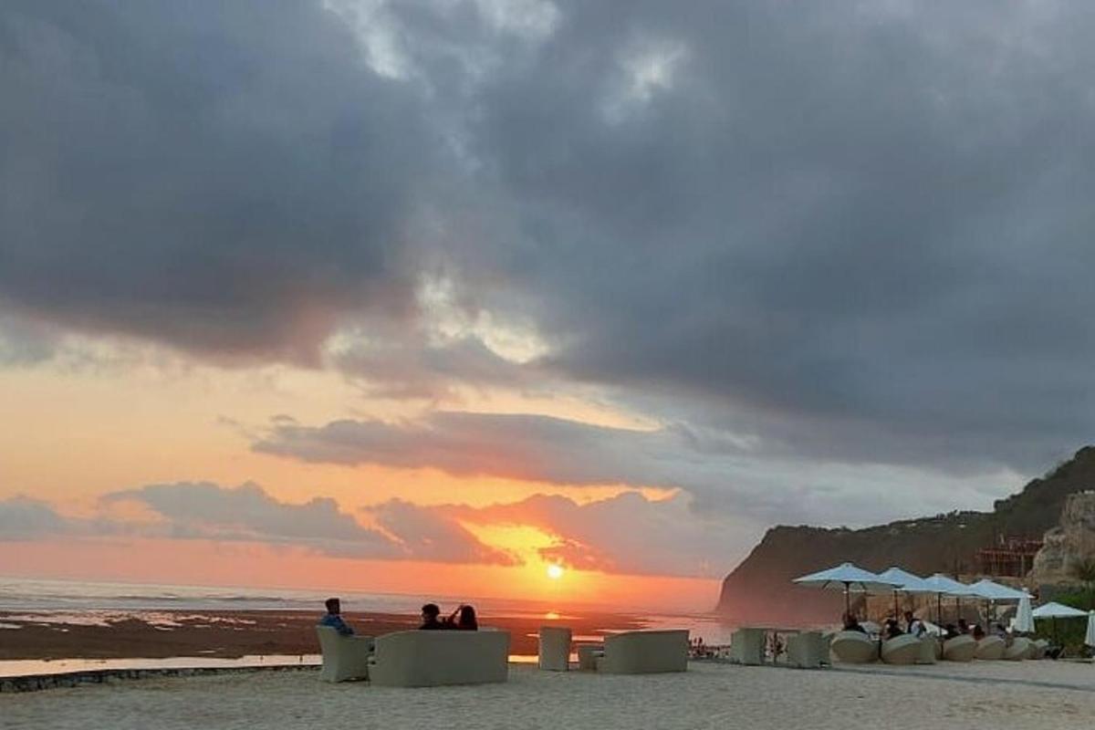 gent asseguda a la platja mirant la posta de sol
