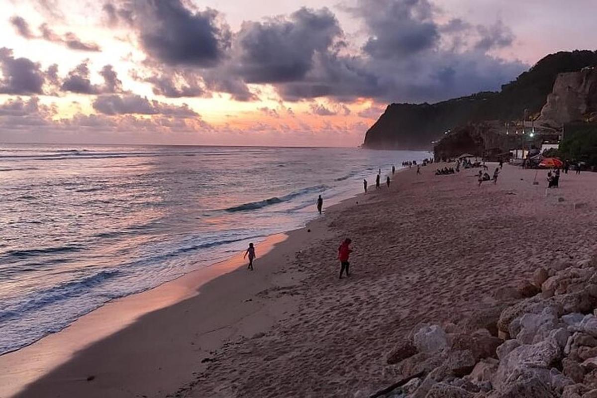 un grup de persones a la platja a la posta de sol
