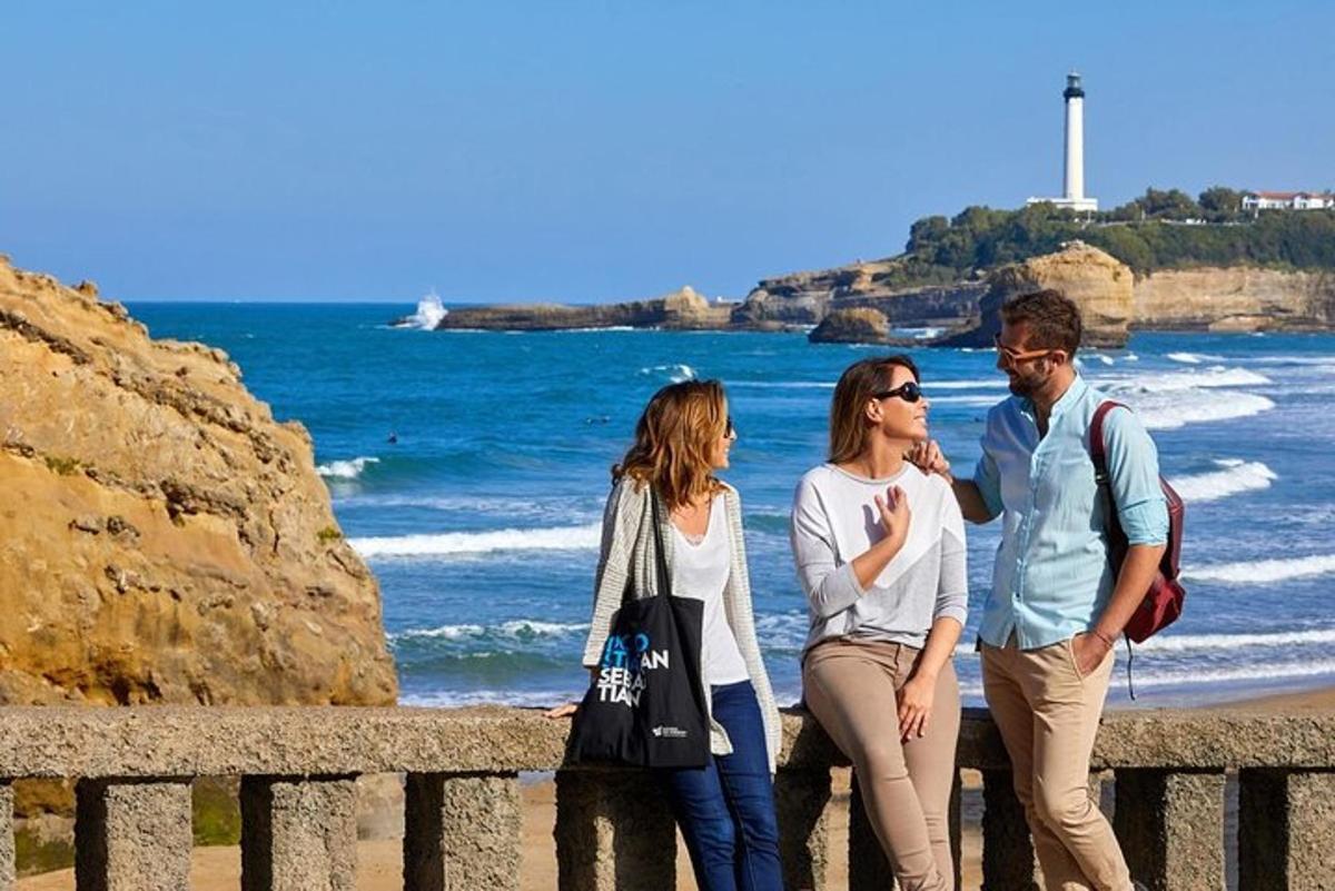 três pessoas em pé em uma cerca perto do oceano
