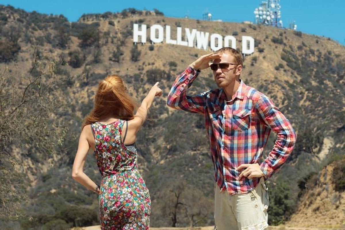 un home i una dona drets davant d'un rètol de Hollywood