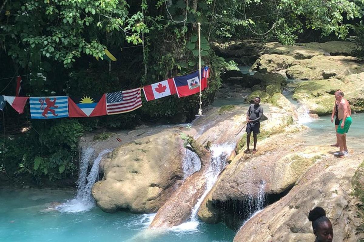 due persone in piedi sulle rocce in un fiume con una cascata