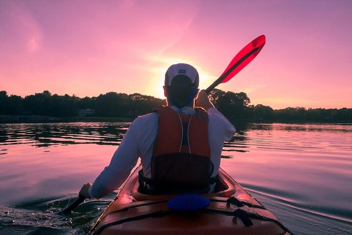 un uomo in kayak sull'acqua al tramonto