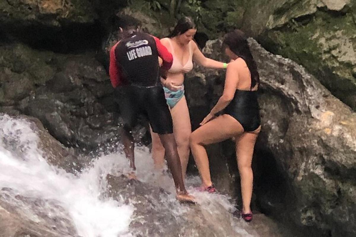 tři lidé stojící na skále ve vodě
