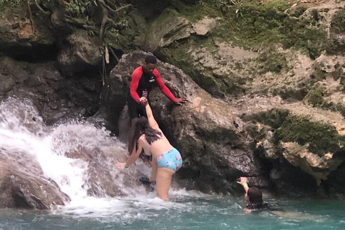a group of people in the water near a waterfall