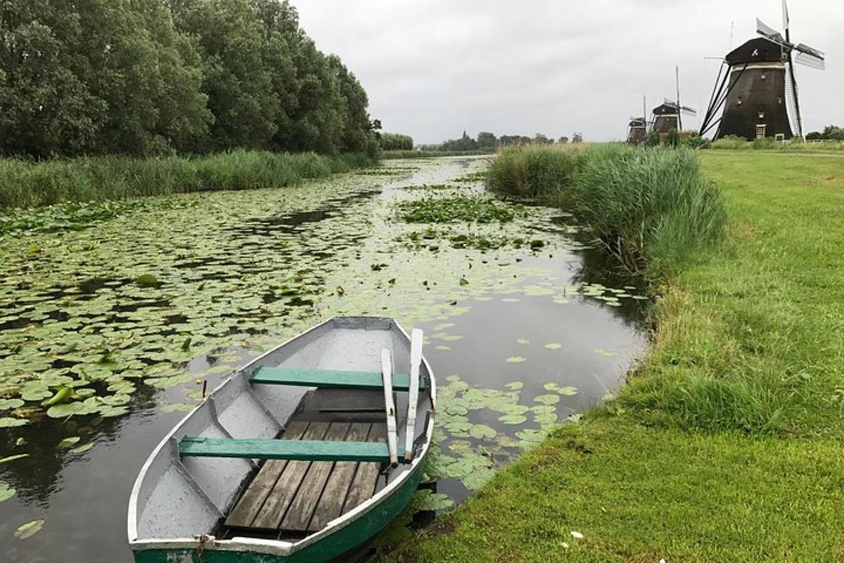 loď kotvící na řece vedle větrného mlýna