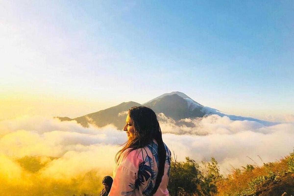 eine Frau steht auf einem Berggipfel mit Wolken