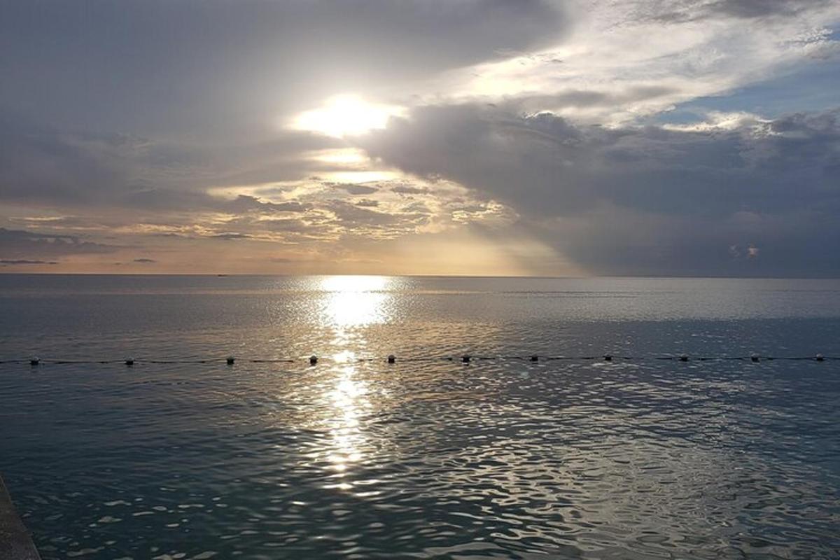 sekelompok orang berenang di laut saat matahari terbenam