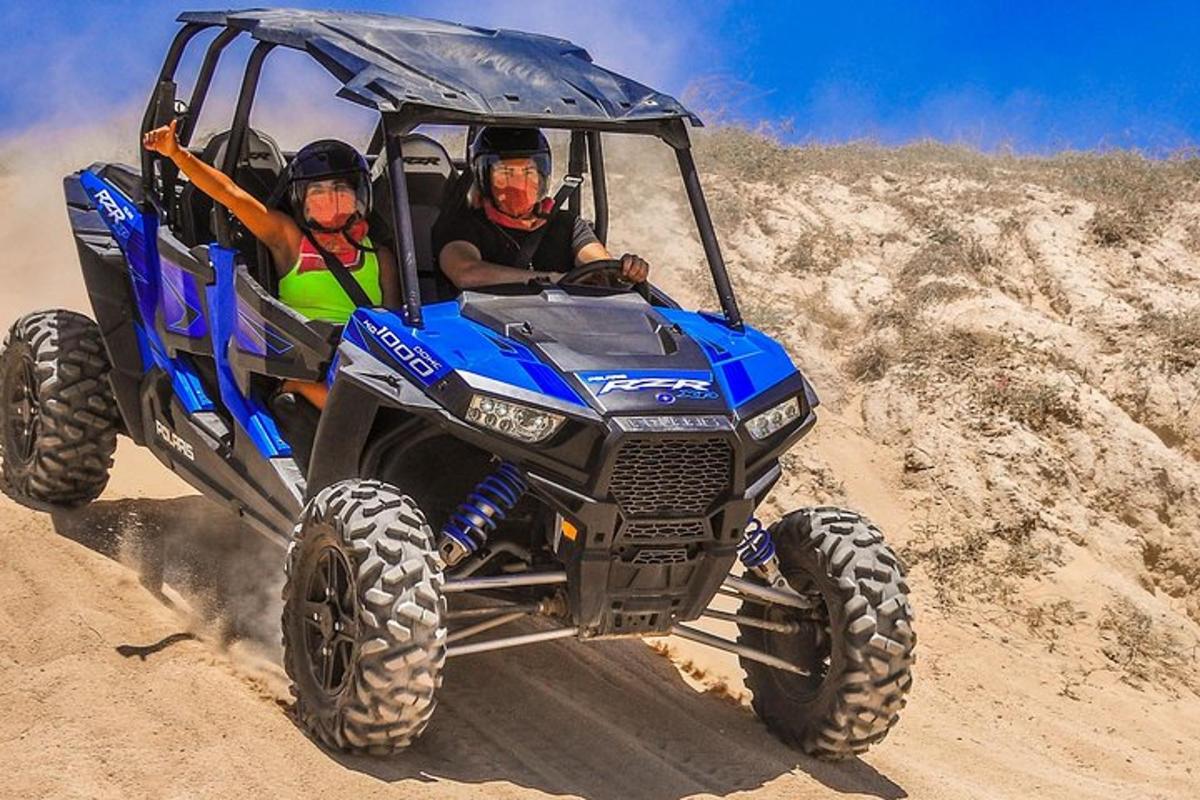 duas pessoas andando em um quadriciclo azul na terra