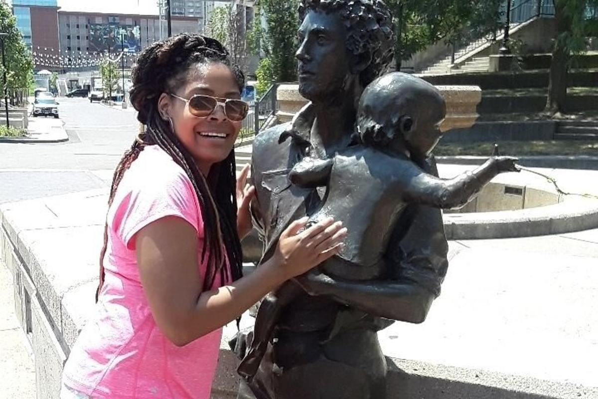 a woman standing next to a statue holding a child