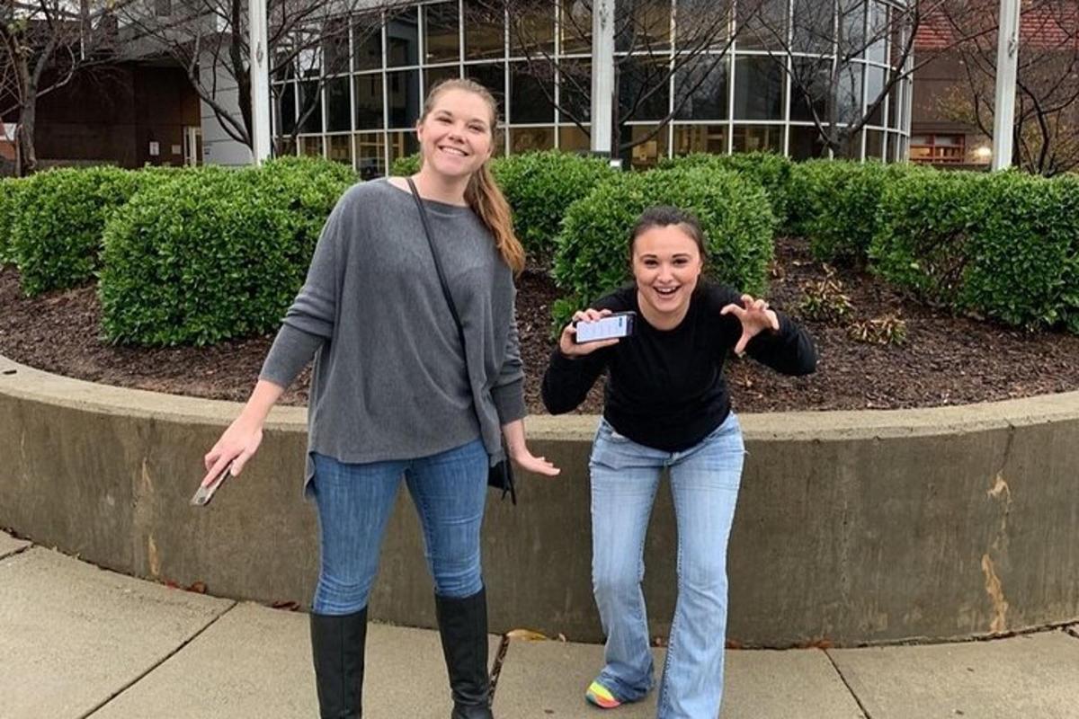 two women standing next to each other on a sidewalk