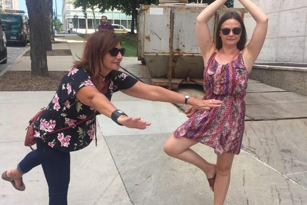 two women are dancing on a sidewalk