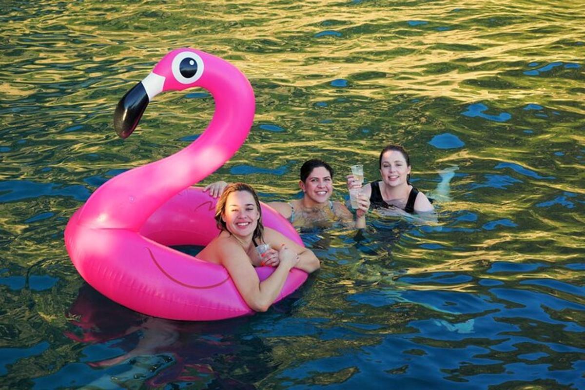 three women in the water with an inflatable pink swan