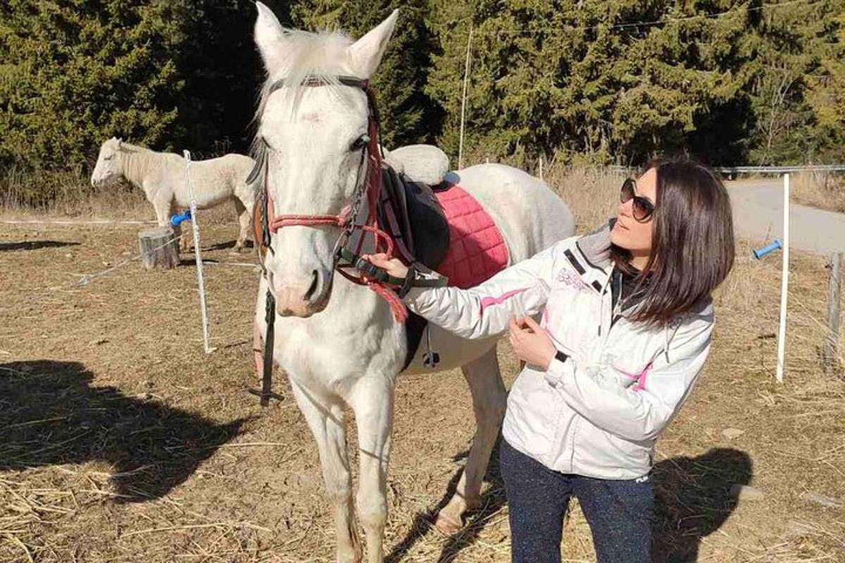 a woman standing next to a white horse