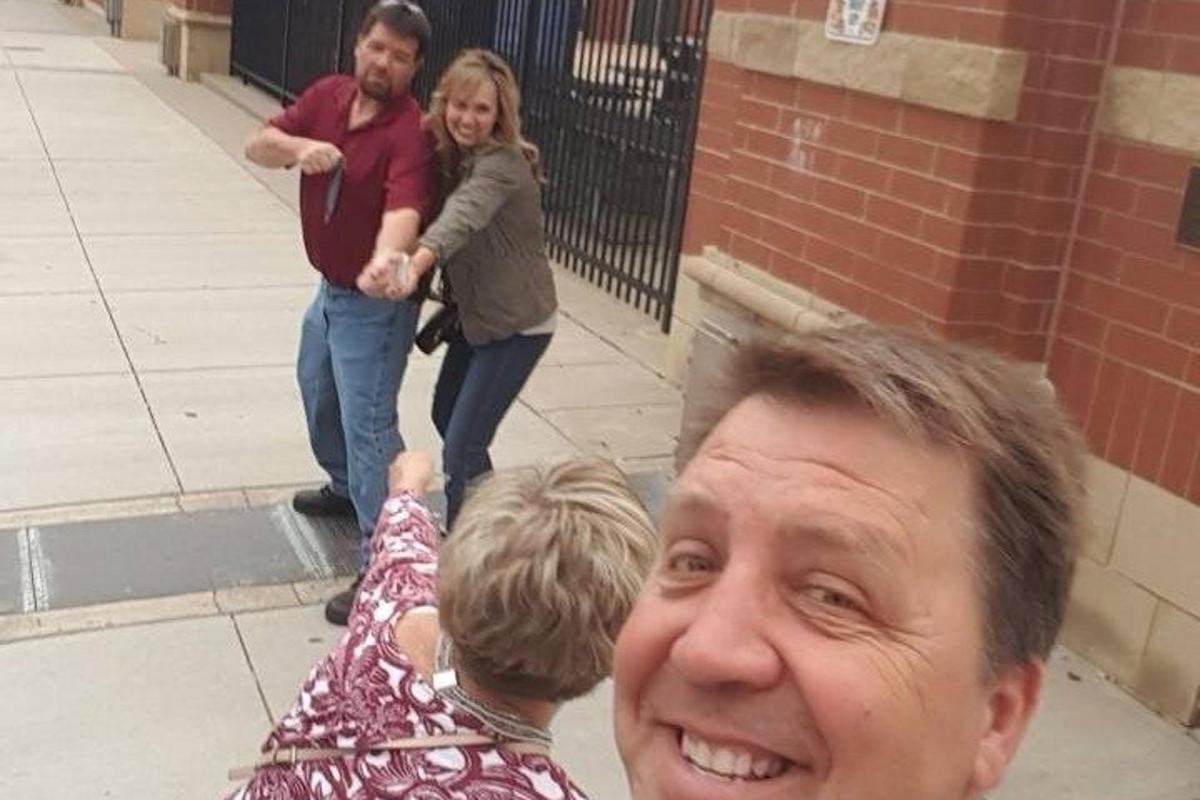 a group of people walking down a sidewalk with a man