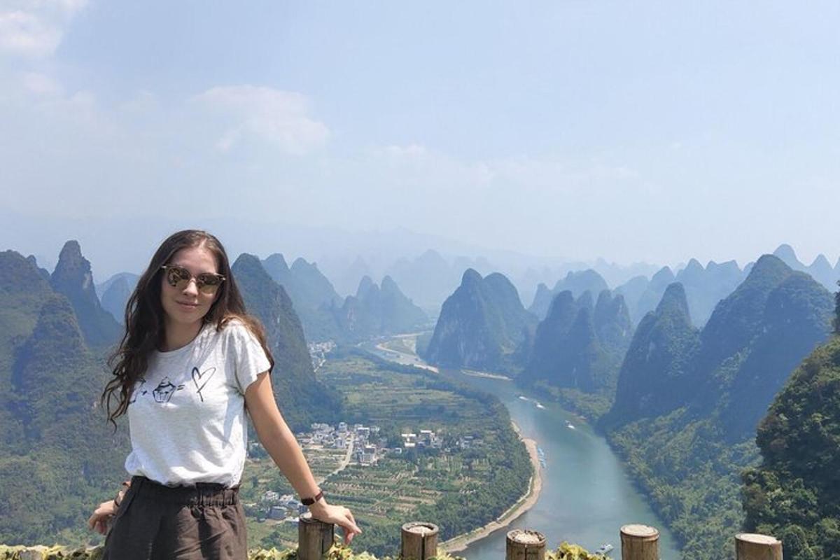 a woman standing on top of a mountain overlooking a river