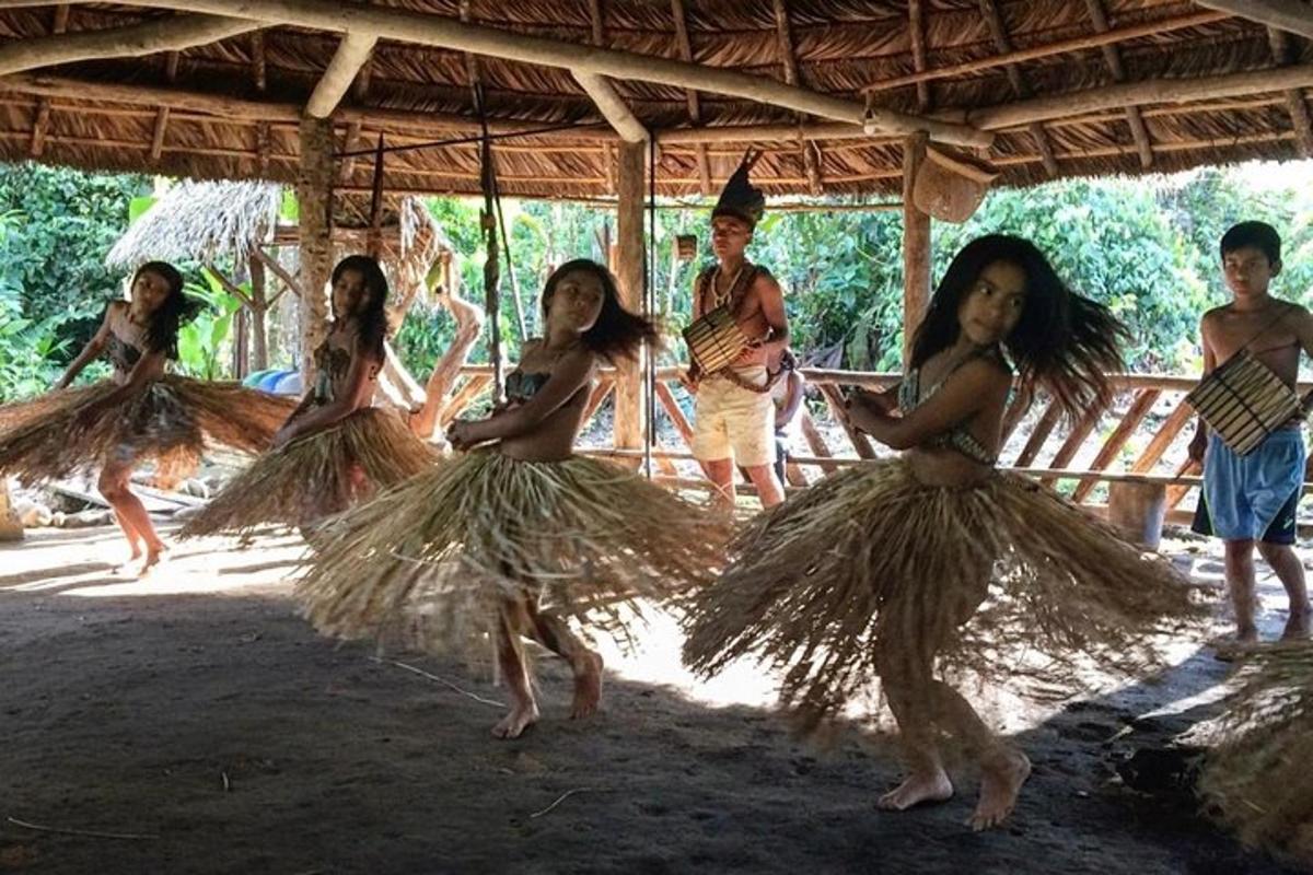 a group of young women in grass skirts standing under a roof