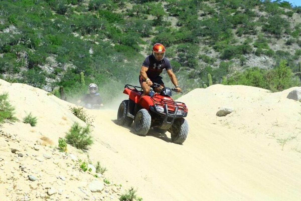 un uomo che guida un quad su una strada sterrata