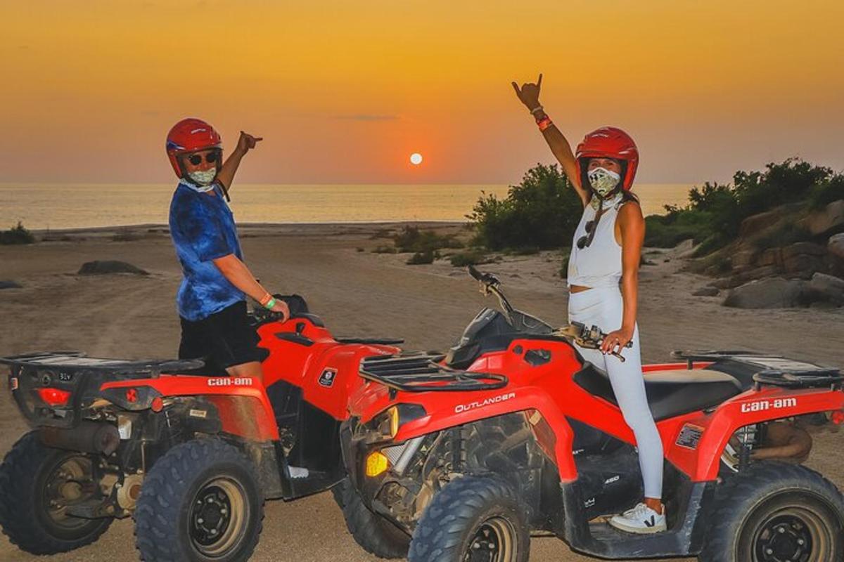 due persone su quad sulla spiaggia al tramonto