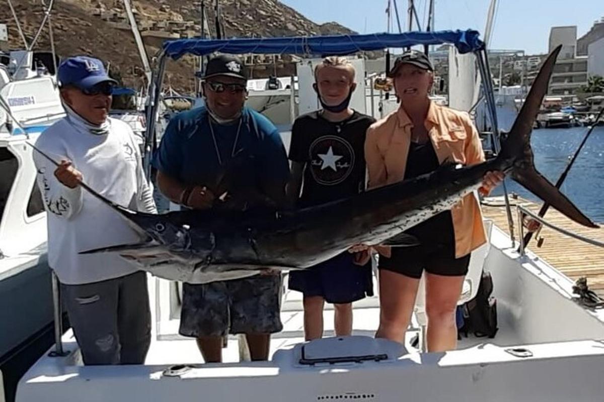 a group of people standing on a boat holding a fish