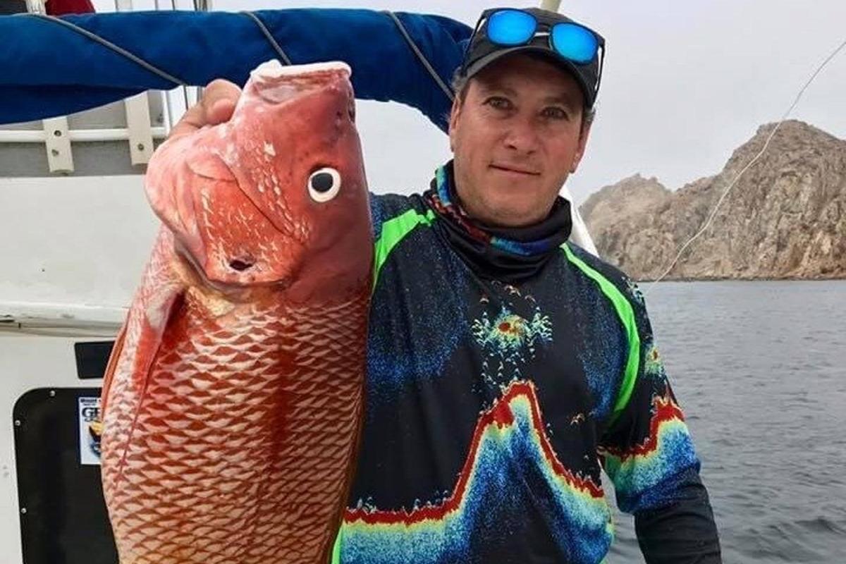 a man holding a fish in his hand on a boat