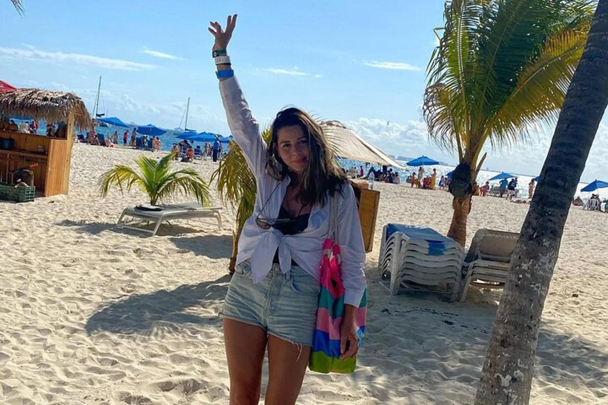 seorang wanita berdiri di pantai dengan tangannya di udara