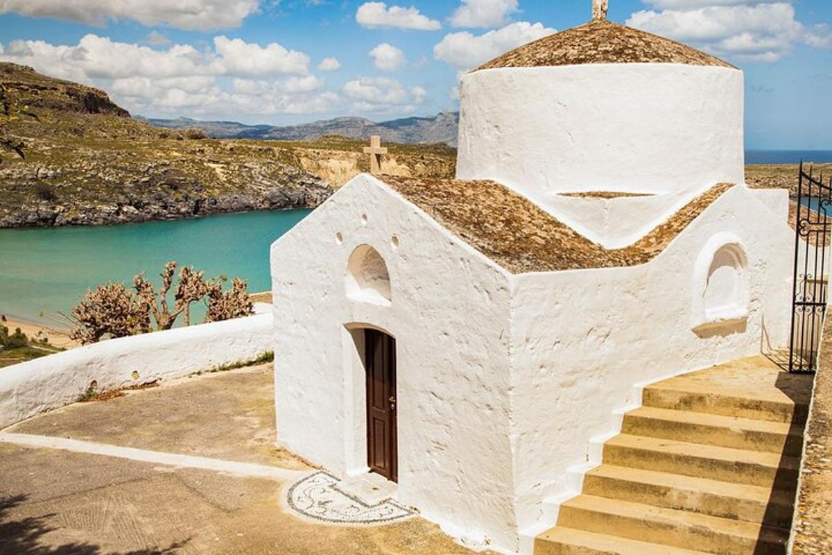 Una iglesia blanca con escaleras al lado de un cuerpo de agua.