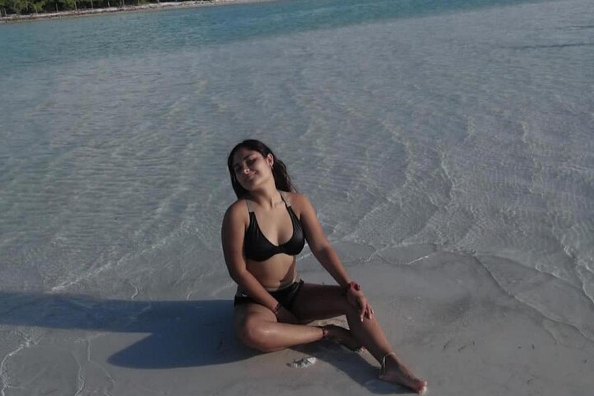 en kvinde i bikini sidder på stranden