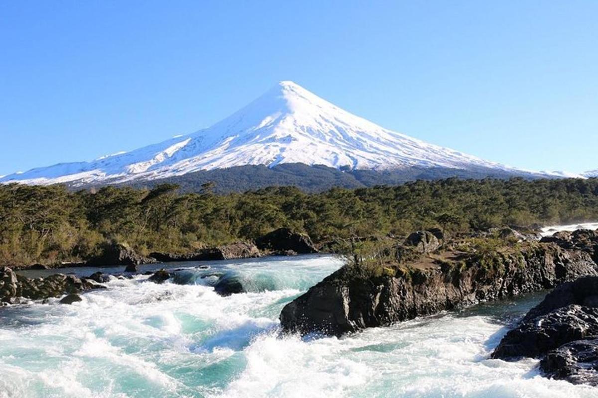 a snow covered mountain in the distance with a river