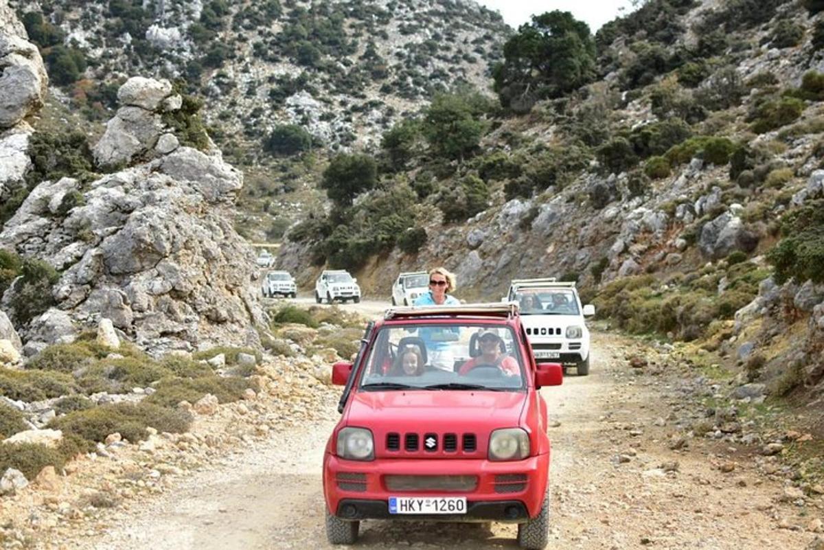 un homme conduisant une jeep rouge sur un chemin de terre