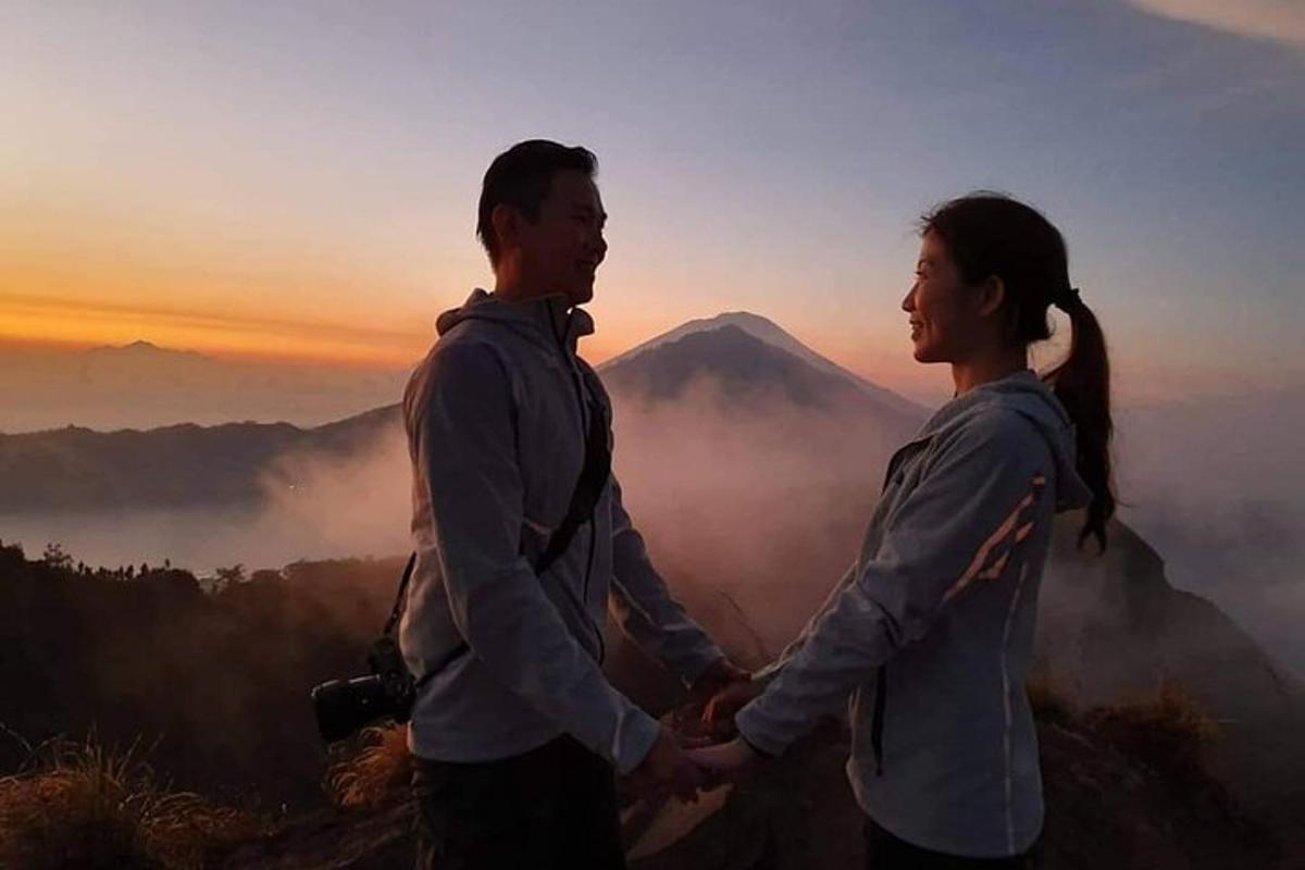 una coppia che si tiene per mano mentre è in piedi sulla cima di una montagna
