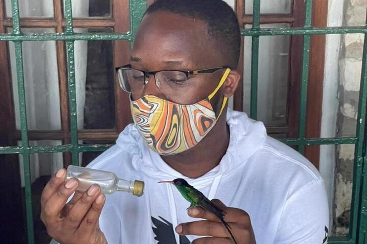 seorang lelaki memakai topeng dengan botol dan seekor burung
