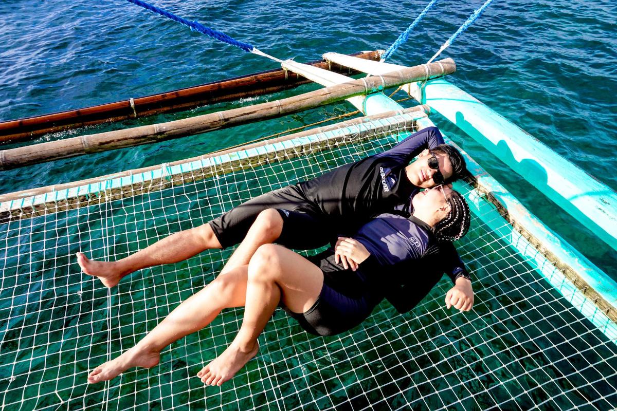 a man and woman laying on a boat in the water