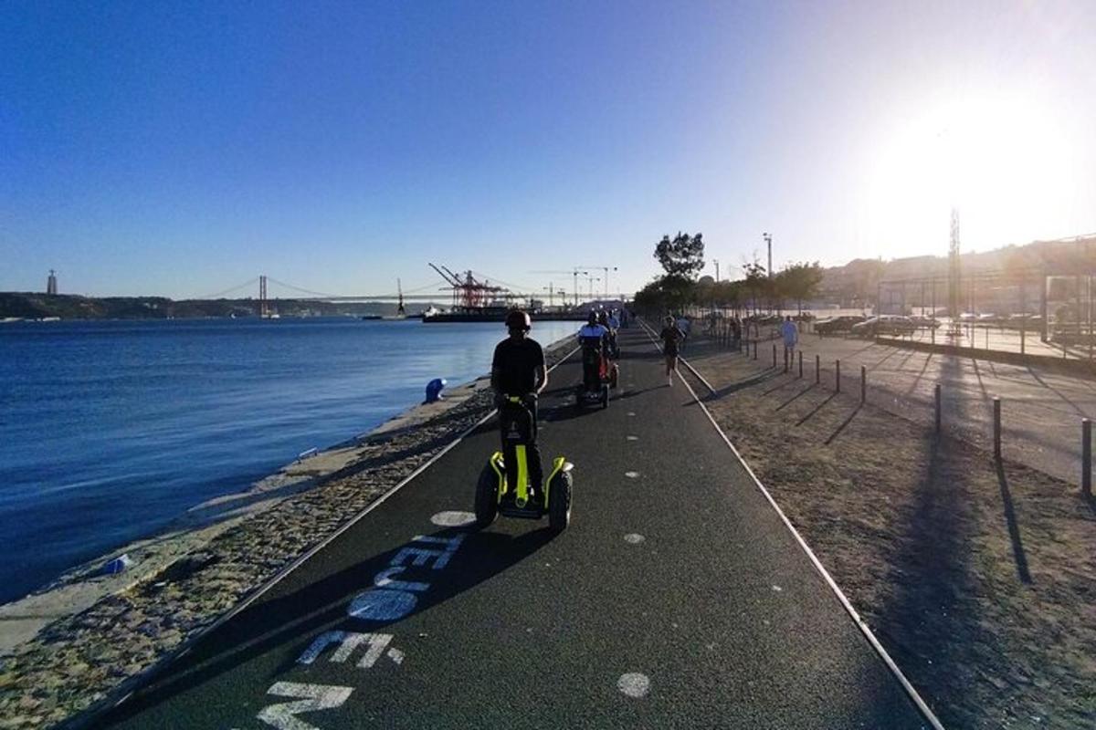 Maður á vespu á gangstétt við vatnið